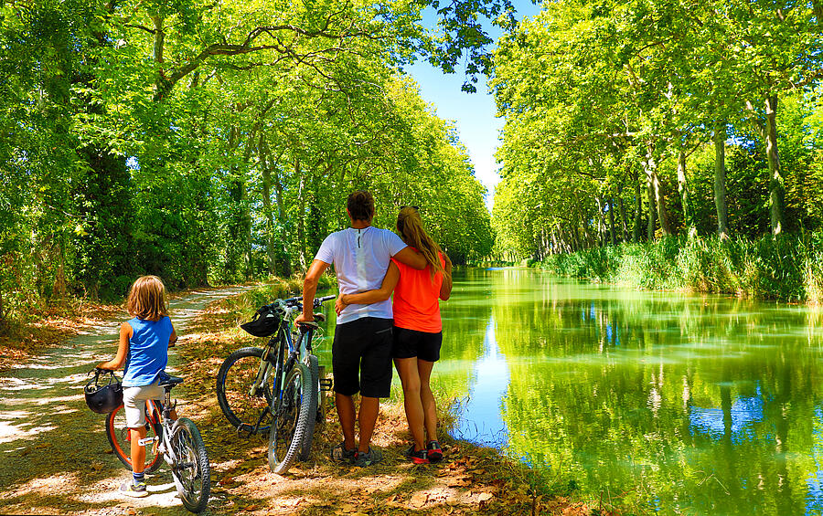 Gezin op fietstocht langs het schaduwrijke pad aan de oevers van het Canal du Midi, midden in de natuur.