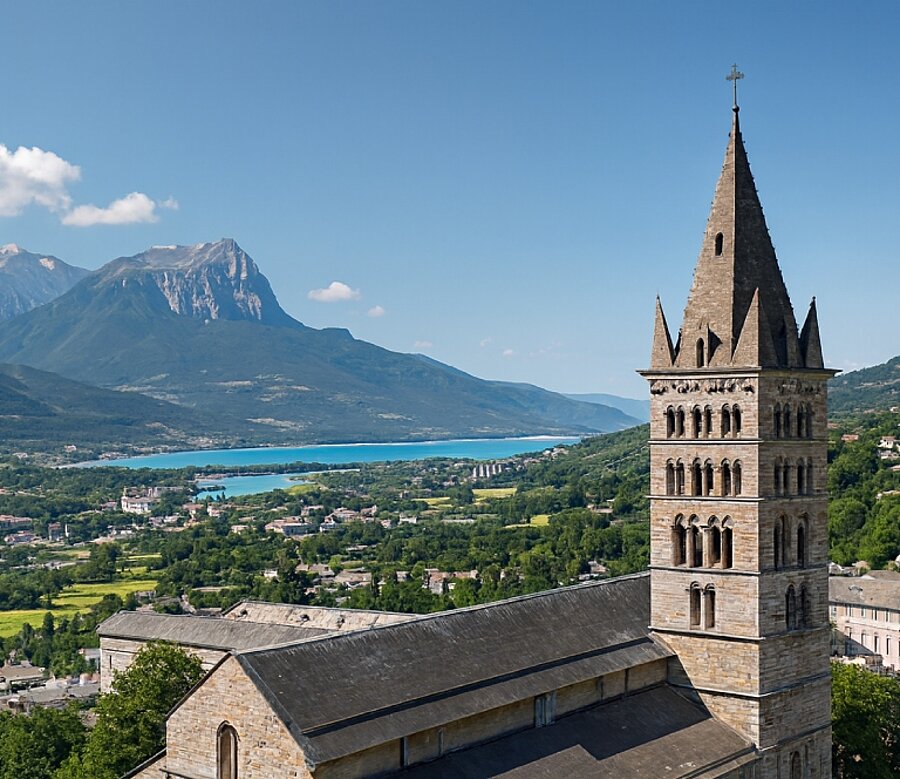 De kathedraal Notre-Dame-du-Réal in Embrun met uitzicht op de stad, de Zuidelijke Alpen en het meer van Serre-Ponçon.