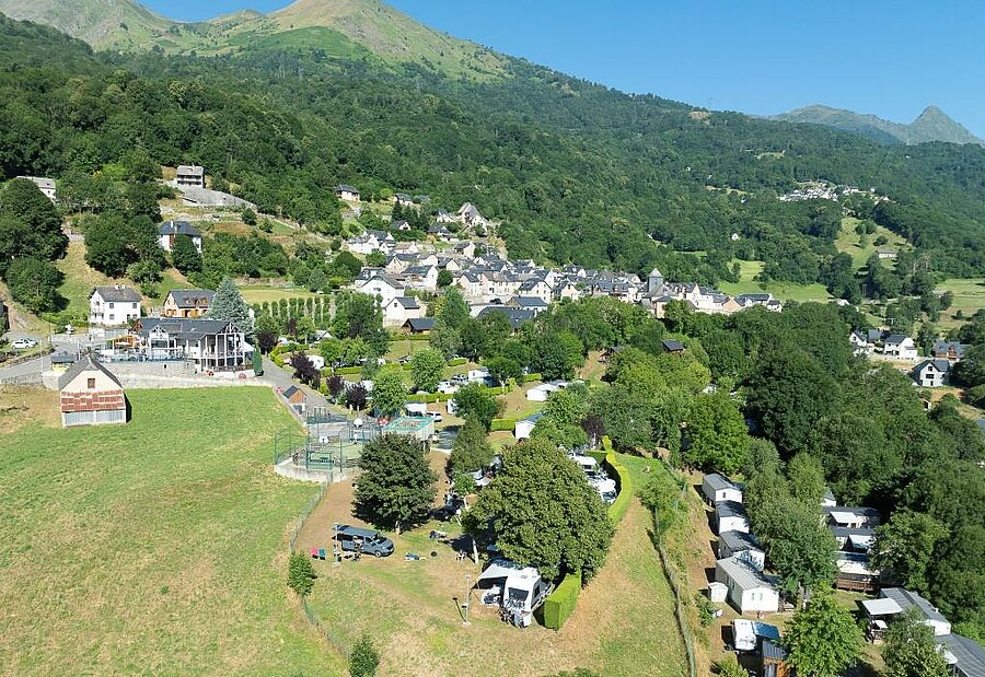 Luchtfoto van een camping in de Pyreneeën, vlak bij een typisch bergdorp in de natuur van Zuid-Frankrijk.