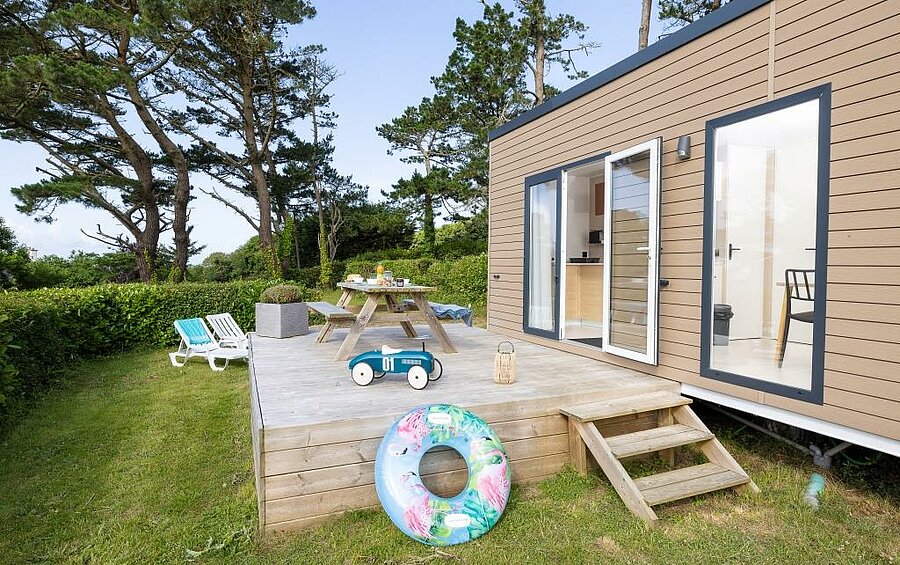 Stacaravan met houten terras, ligstoelen en picknicktafel op een gezinsvriendelijke camping in Bretagne