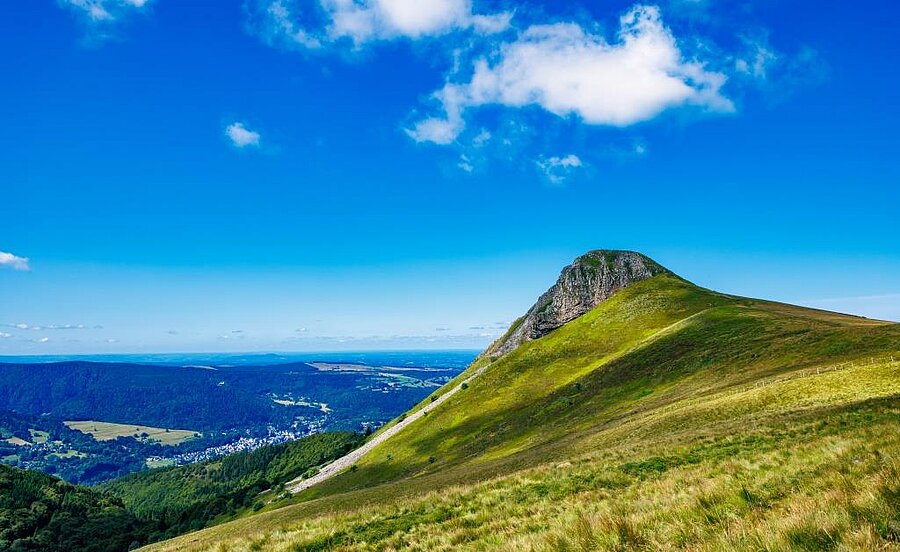 Vulkanisch landschap van Auvergne met een groene top en een wijds uitzicht over het dal.
