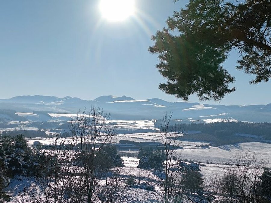 Besneeuwd winterlandschap met panoramisch uitzicht op de bergen onder een stralende zon. Een ongerept natuurdecor, ideaal voor een verblijf op een caravansneeuw-camping met Sites et Paysages.