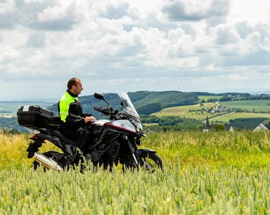 Motorrijder omringd door groen op een schilderachtig pad