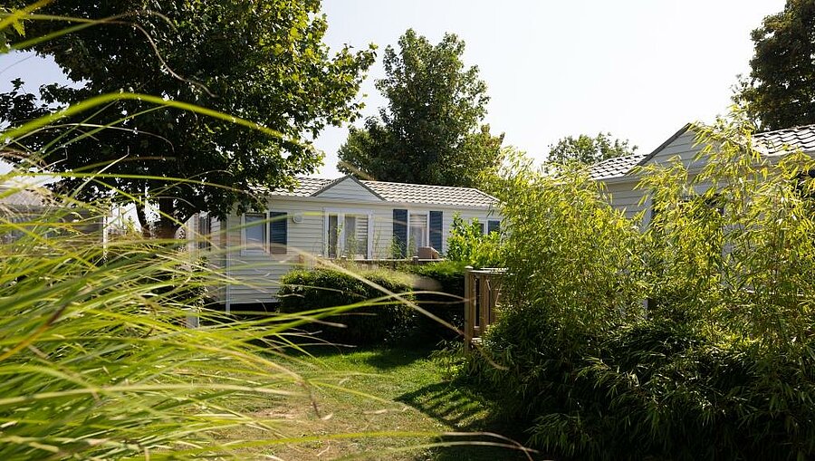 Moderne stacaravan omringd door groen op camping in de Opaalkust, ideaal voor een comfortabele gezinsvakantie.