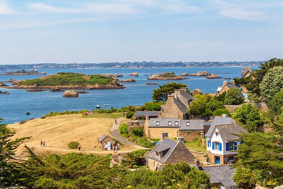 Uitzicht op het eiland Bréhat bij Paimpol, stenen huizen en groene eilandjes in de turquoise zee van Noord-Bretagne.