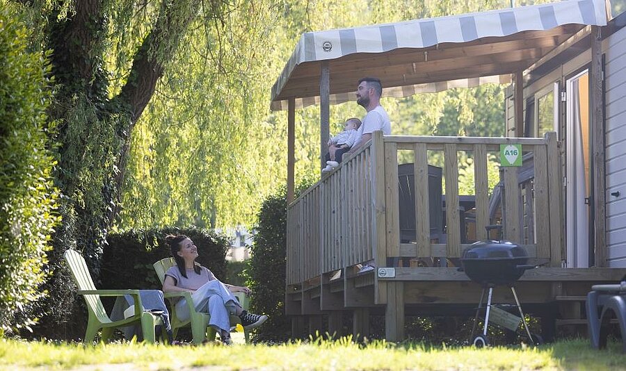 Stacaravan huren in Normandië op de camping, gezin geniet van een ingericht terras midden in de natuur voor een ontspannen verblijf.