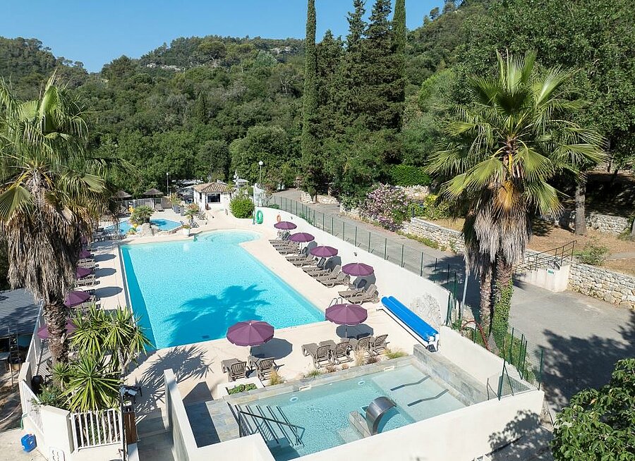 Zwembad omringd door ligstoelen en palmbomen op een campsite aan de Côte d’Azur, een ideale omgeving voor een familievakantie