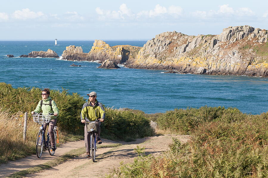 Een stel fietst en geniet van het natuurlijke landschap bij de camping in Cancale, Bretagne, met uitzicht op de Pointe du Grouin.