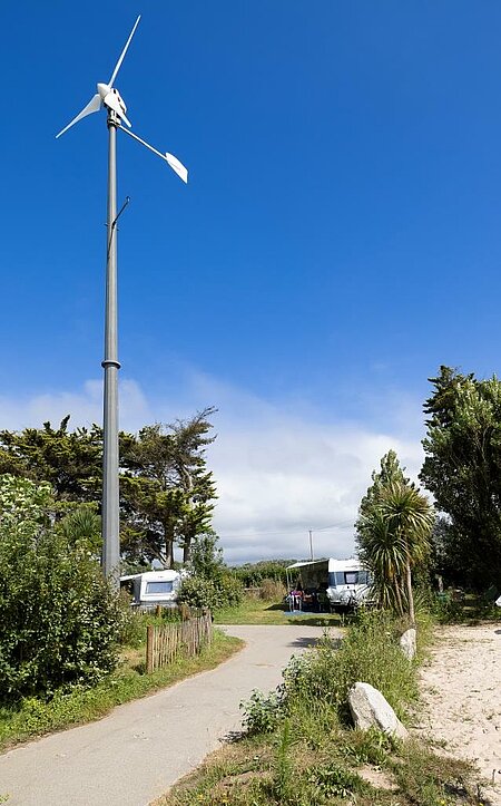 Windmolen op een charme camping, als symbool van het gezamenlijke engagement van Sites et Paysages voor duurzaam toerisme en hernieuwbare energie.