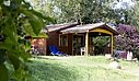 Houten chalet op een camping, omringd door groen, met comfortabel verblijf voor een vakantie midden in de natuur.