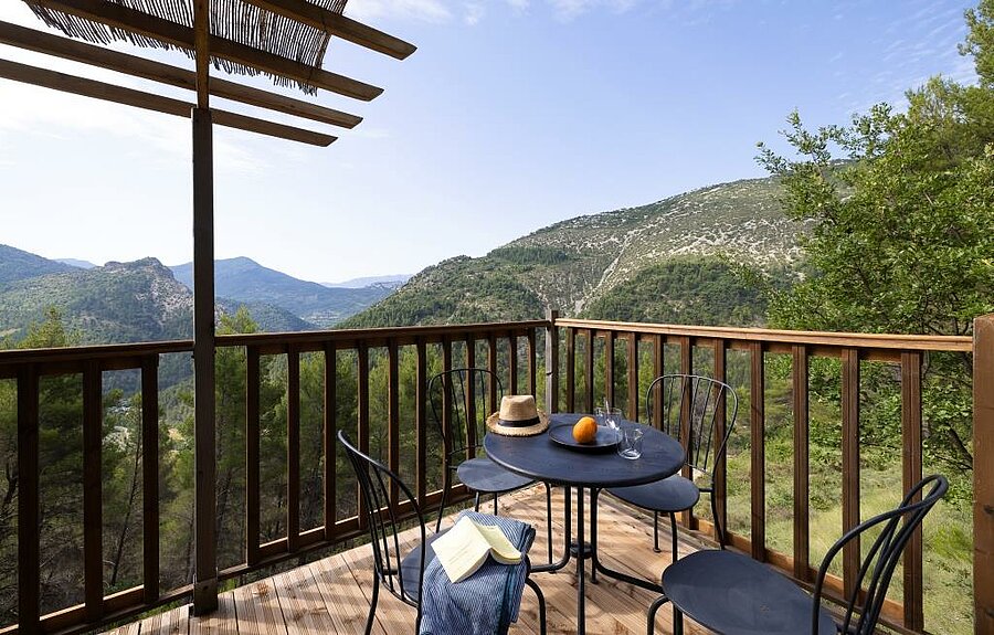 Houten terras van een campsite-accommodatie in de Drôme met panoramisch uitzicht op de groene heuvels