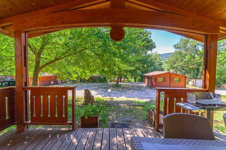 Uitzicht vanaf het terras van een houten chalet op een Sites et Paysages camping, perfect voor een ontspannen verblijf tijdens de meivakantie.