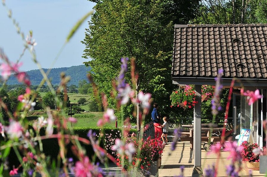 Gezin op het bloementerras van een campingaccommodatie met uitzicht op de natuur in Bourgogne-Franche-Comté.