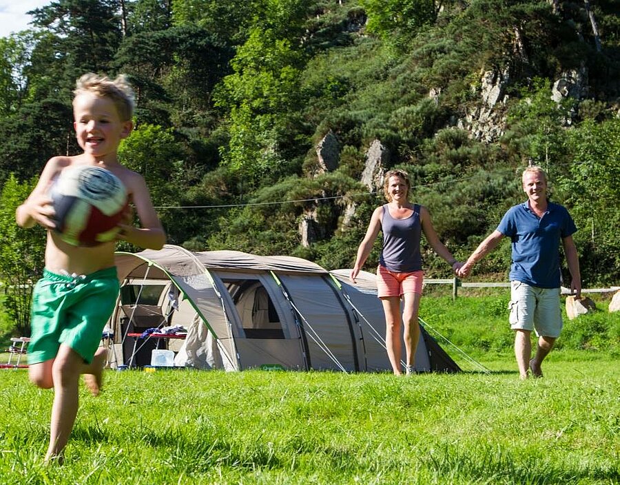 Gezin met kind dat speelt voor een tent op een ACSI camping, natuurverblijf op een ruime en voordelige plaats.