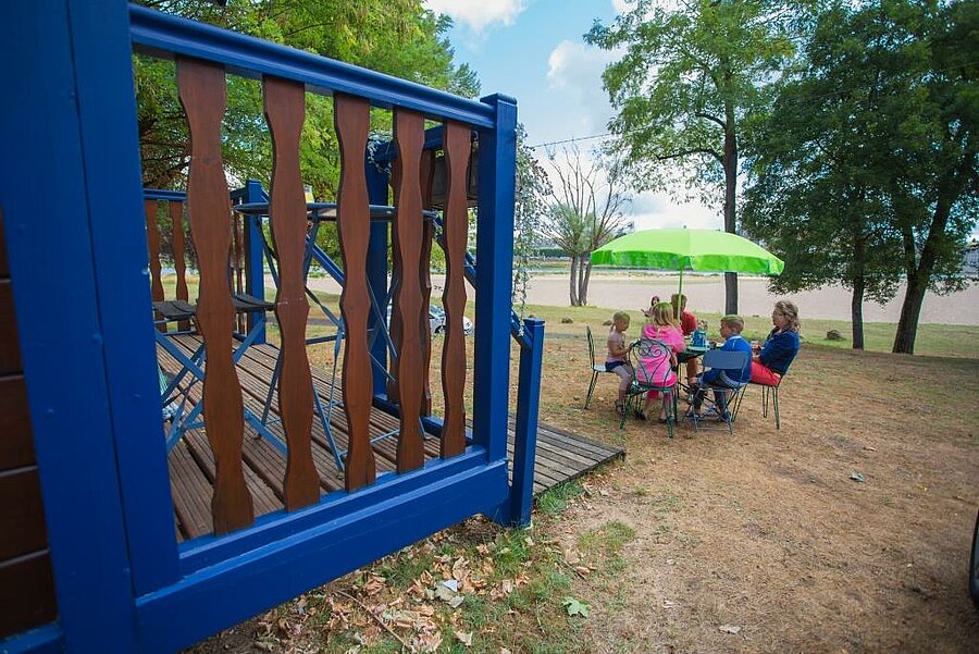 Een gezin ontbijt gezellig in de buitenlucht voor een kleurrijke pipowagen op een charme camping bij de Sologne, met uitzicht op de Loire.