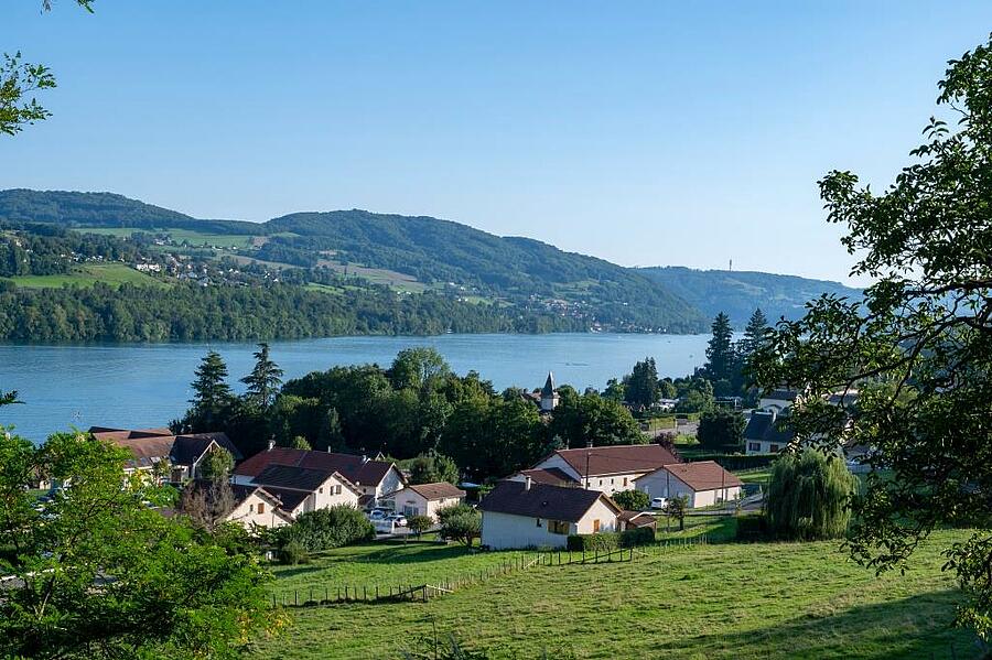 Panoramisch uitzicht op het meer van Paladru in de Isère, omringd door groene heuvels en charmante dorpjes – de ideale plek voor een kampeervakantie vol natuur en waterpret.