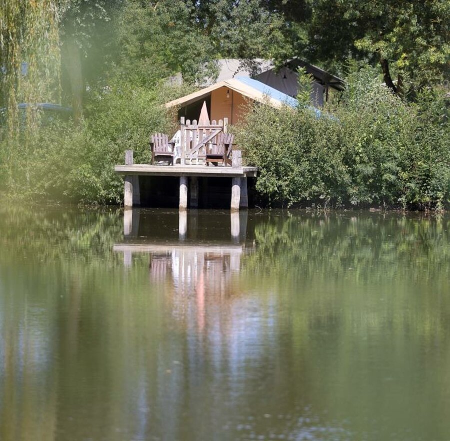 Comfortabele lodge tent met houten terras boven een vijver, midden in de natuur – perfect voor een bijzonder verblijf vlak bij de kastelen van de Loire.