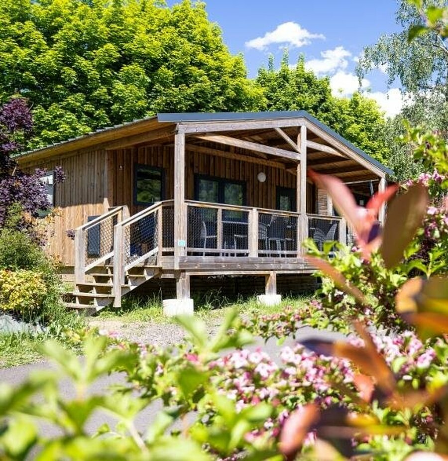 Houten chalet midden in het groen op een camping bij Besse-et-Saint-Anastaise, comfortabele accommodatie voor een gezinsvakantie.