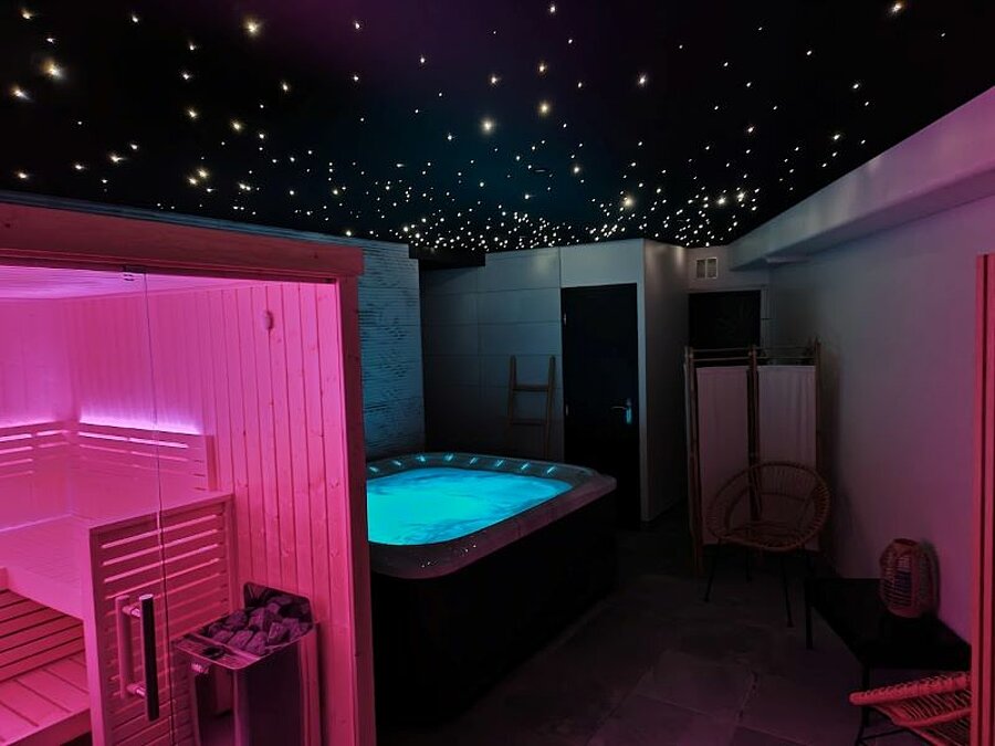 Wellnessruimte met spa, sauna en sterrenverlichting, ideaal om te ontspannen na een dag op een caravaneige-camping. Een rustgevende ervaring midden in de winter.