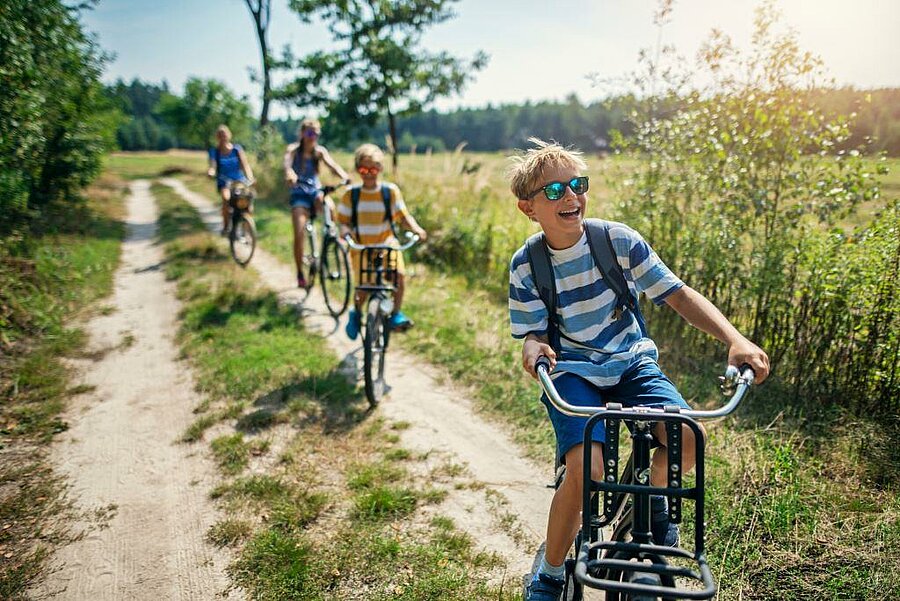 Lachende kinderen op de fiets op een landweg in Loir-et-Cher, natuurvakantie op een gezinscamping