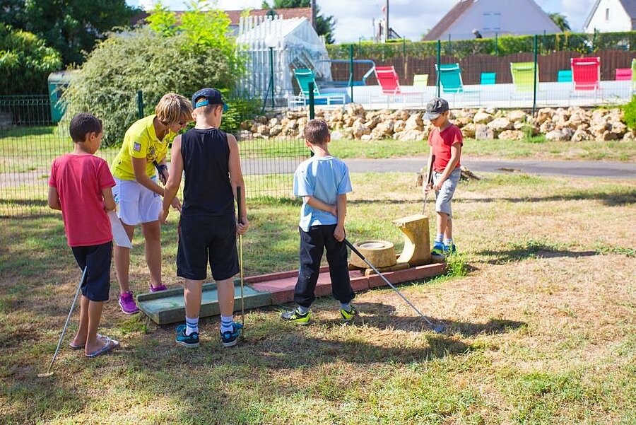 Kinderen spelen minigolf onder toezicht van een animatrice op een gezellige charme camping bij de Sologne, vlak bij Gien.