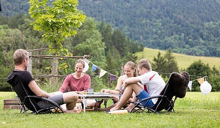 Gezin verzameld rond een spel in de volle natuur, als symbool van de waarden van duurzaam toerisme uit de gids voor de verantwoorde vakantieganger van Sites et Paysages.