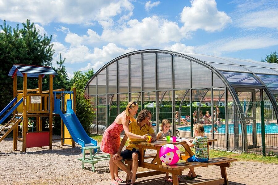 Gezin op vakantie op een campsite in de Vogezen met speeltuin en overdekt zwembad – perfect voor ontspannen momenten met de kinderen