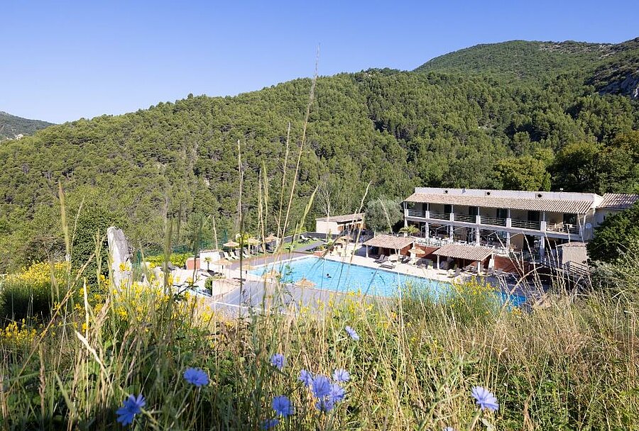 Zwembad van een campsite omgeven door beboste heuvels in de Drôme, perfect voor een natuurvakantie met het gezin