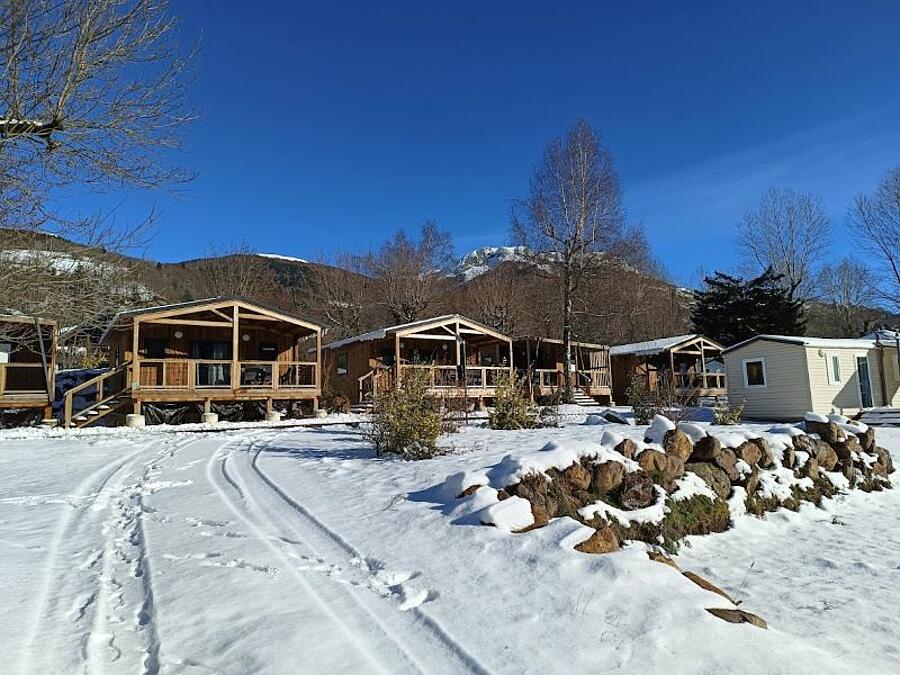 Houten chalets in een besneeuwde camping, die een onderdompeling in de winterse natuur bieden.