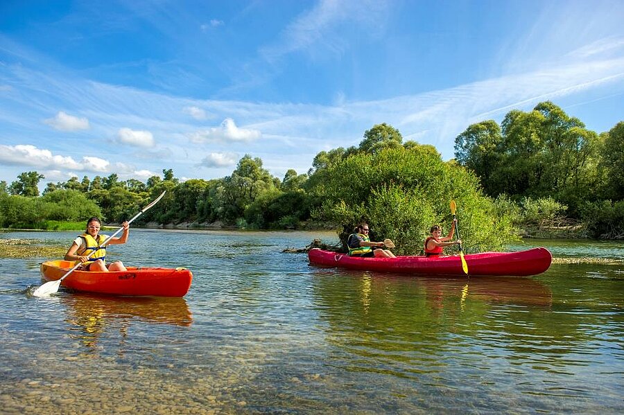 Een gezin in een kano op een rivier, midden in de natuur, geniet van activiteiten dankzij de gratis reserveringskosten op een betaalbare camping.
