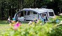 [Translate to Néerlandais:] Famille installée sur un emplacement de camping pour caravane, en pleine nature, dans un cadre verdoyant et ombragé.