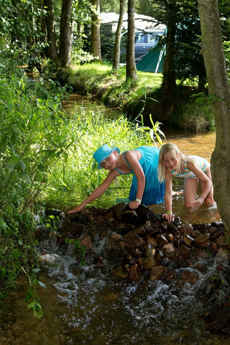 Kinderen spelen in een beekje vlak bij hun tent, een authentieke ervaring voor een weekend familie op de camping.