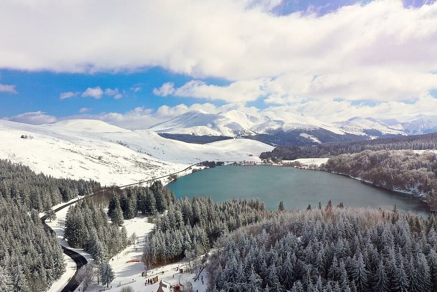Luchtbeeld van het besneeuwde meer van Guery in het Sancy-massief, natuurplek voor camping bij skistation dicht bij de toppen.