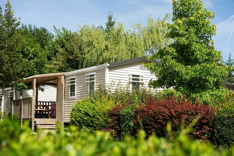 Mobil-home omringd door groen op campsite Beauregard, een comfortabele accommodatie voor een vakantie nabij Lons-le-Saunier.