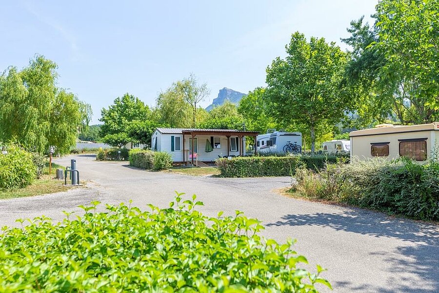 [Translate to Néerlandais:] Allée et hébergements du camping Les Prés Hauts à Sisteron, avec vue sur les Alpes