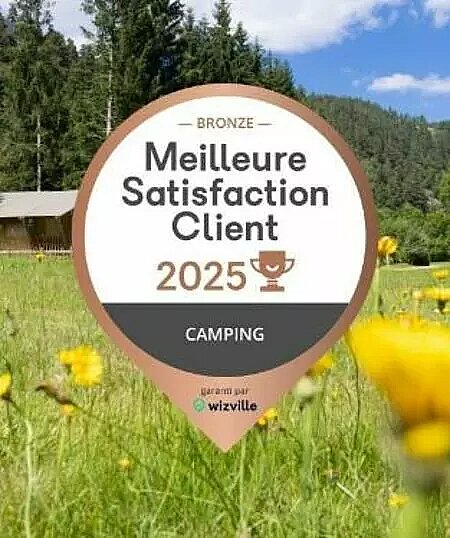 Bronzen badge Beste Klanttevredenheid 2025 op de achtergrond van een weide en bos, symbool voor kleinschalige campings.