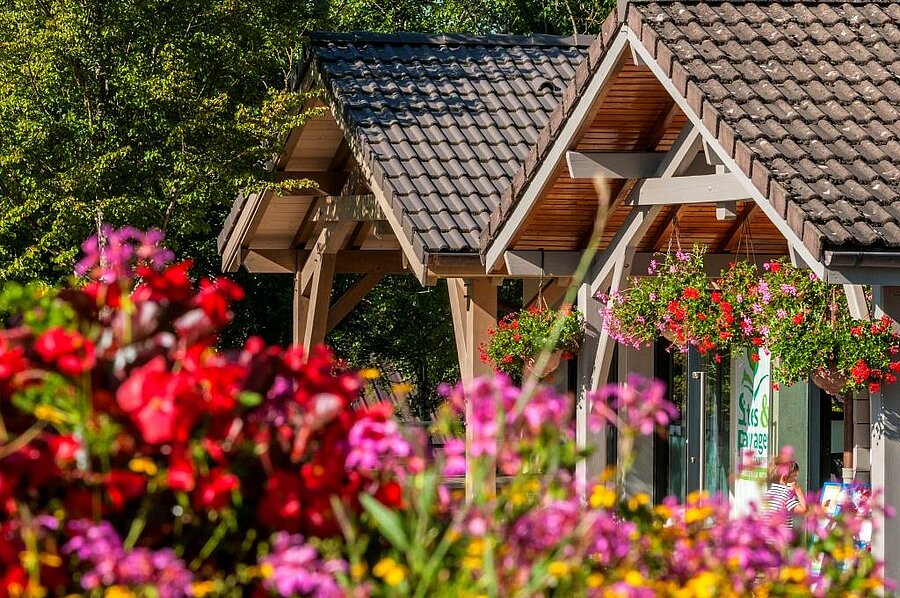 Bloemrijke ingang van de camping in Clairvaux-les-Lacs, warme en natuurlijke sfeer voor een vakantie in de Jura.