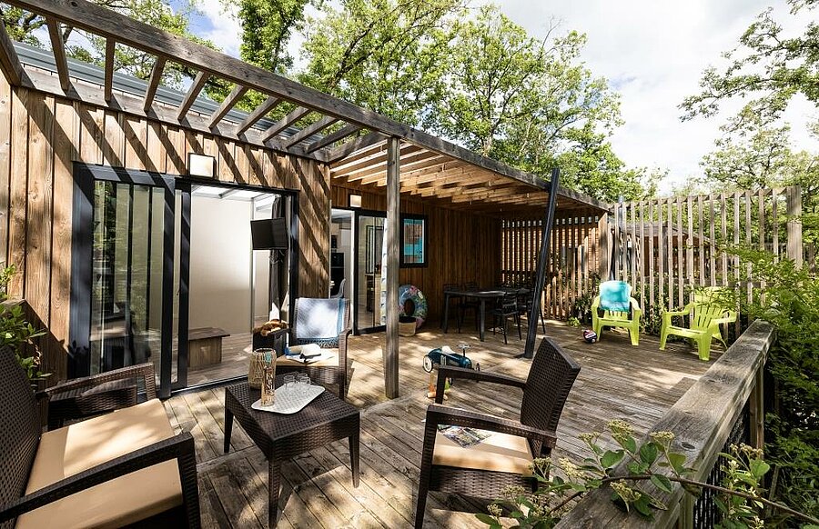 Premium camping met volledig ingerichte accommodatie, houten terras, tuinmeubilair en natuur voor een luxe glampingvakantie.