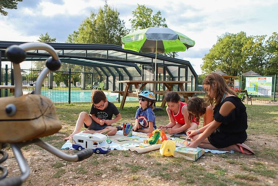 Kinderen spelen samen bij het zwembad van de camping
