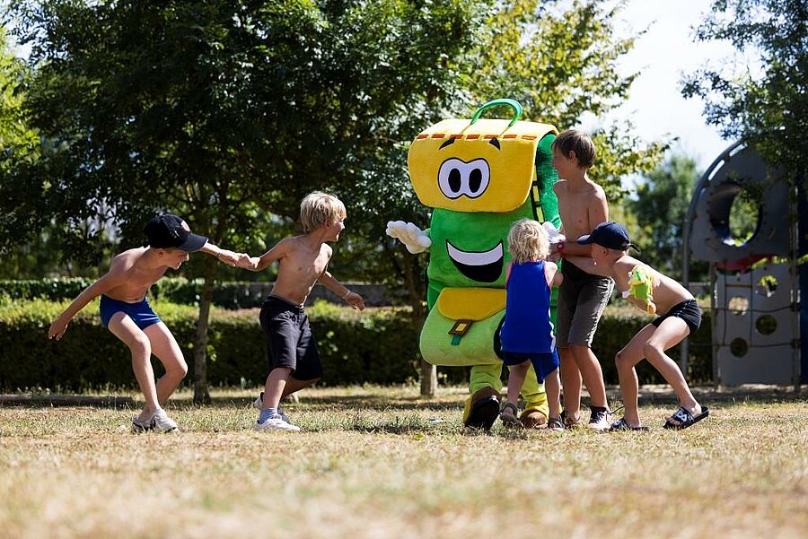 Groep kinderen speelt met een vrolijke mascotte op een gezinscamping in Pays de la Loire, gezellige sfeer.