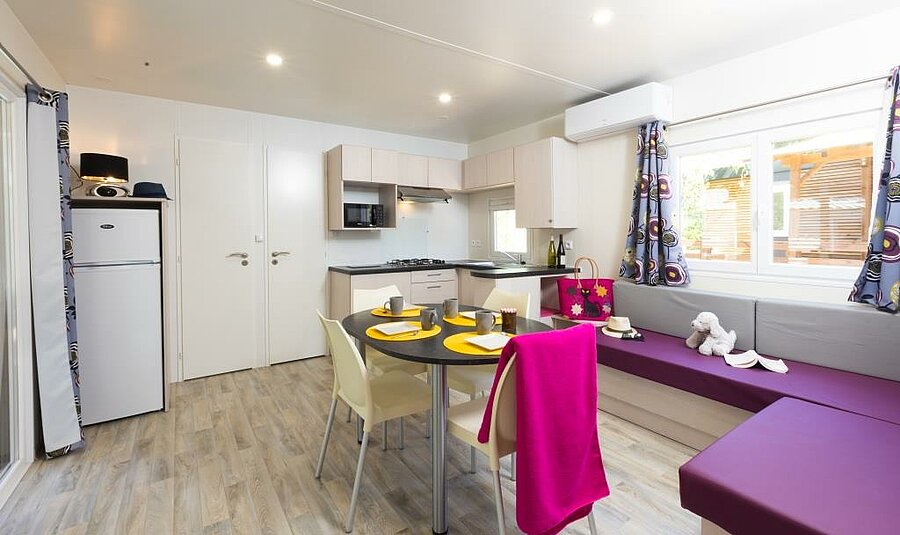 Woonkamer en keuken van een stacaravan met airconditioning, perfect voor een koele gezinsvakantie, zelfs tijdens een hittegolf.