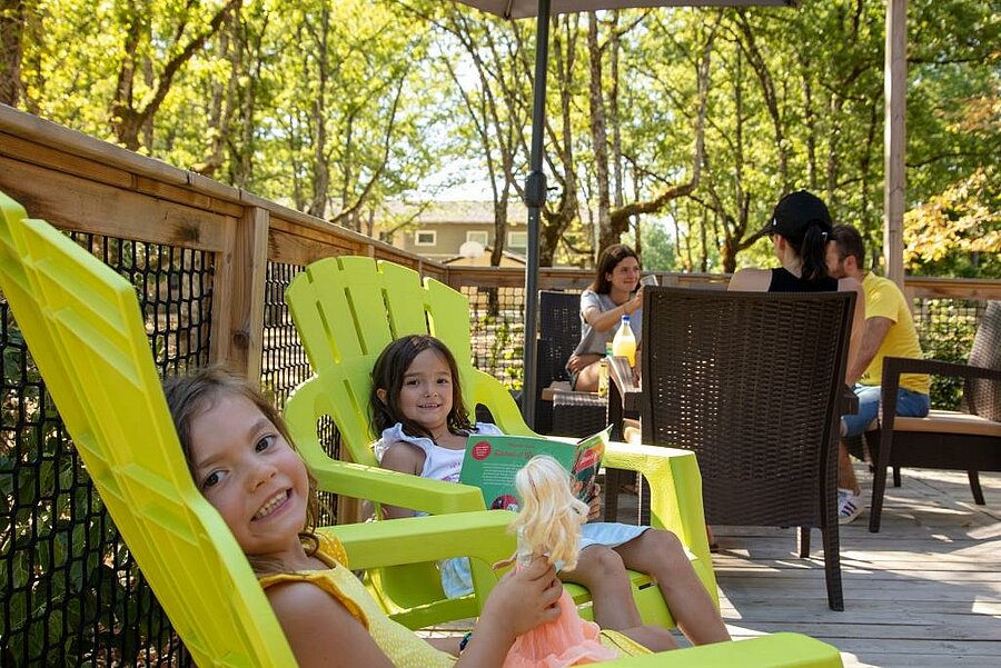 Kinderen ontspannen op het terras van een stacaravan, gezellige sfeer voor last minute camping in augustus met gezin.