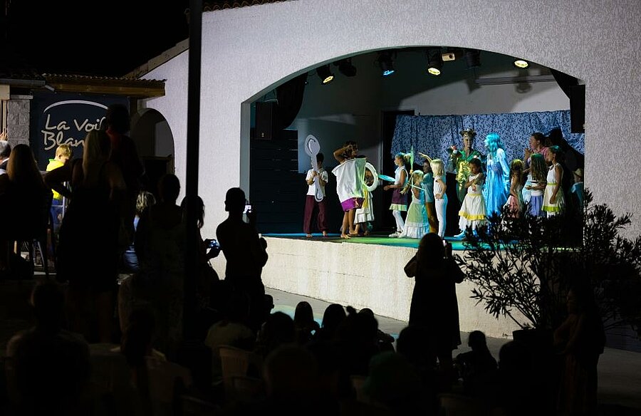 Kinderen op het podium tijdens een campingshow, gezinnen genieten samen van een gezellige animatie op eigen tempo.